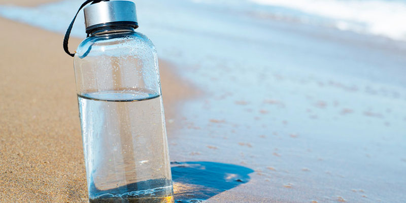 https://www.fluencecorp.com/wp-content/uploads/2022/05/reusable-glass-bottle-on-beach-image.jpg